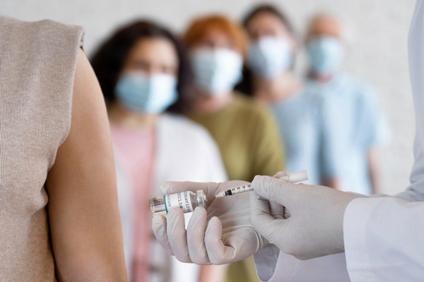 A person holding a syringe and a mask, ready to administer medical treatment or vaccinations.