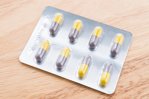 A pack of pills on a wooden table.